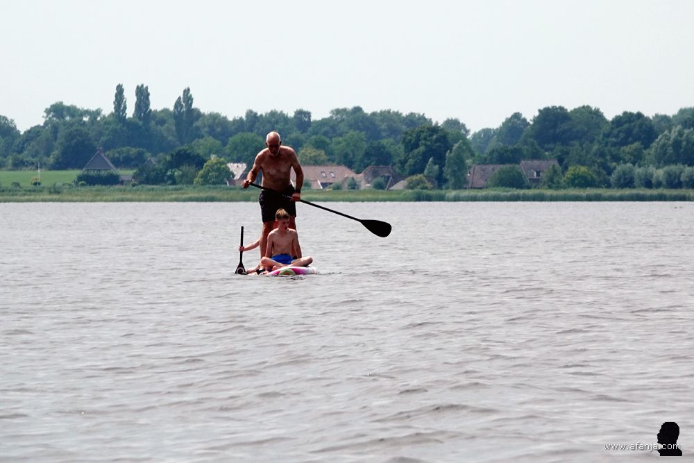 een man geeft zijn (klein)kinderen een rondvaart op een supplank