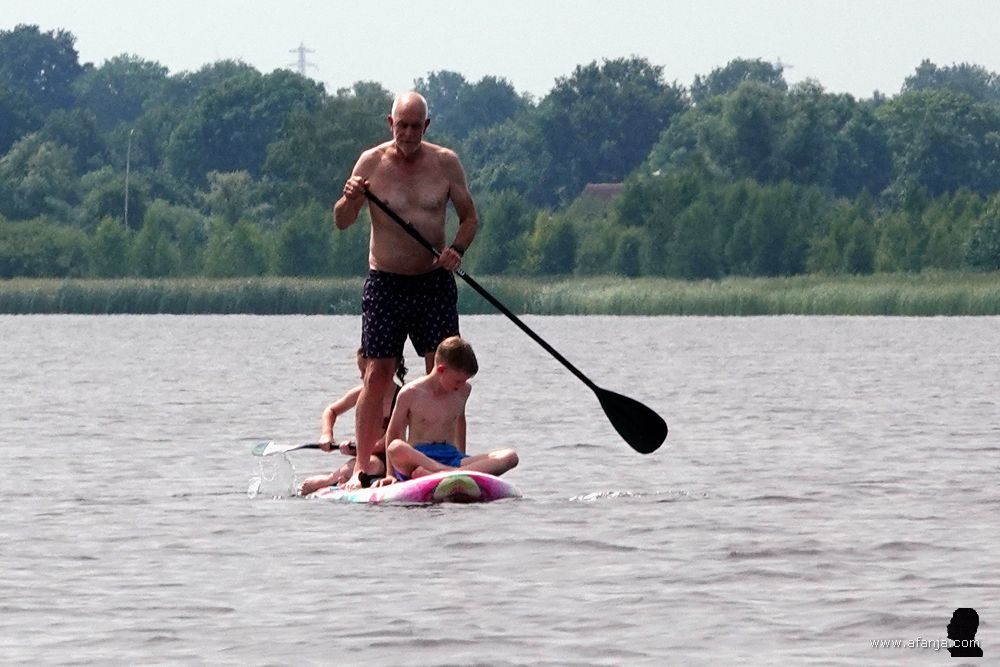 een man geeft zijn (klein)kinderen een rondvaart op een supplank