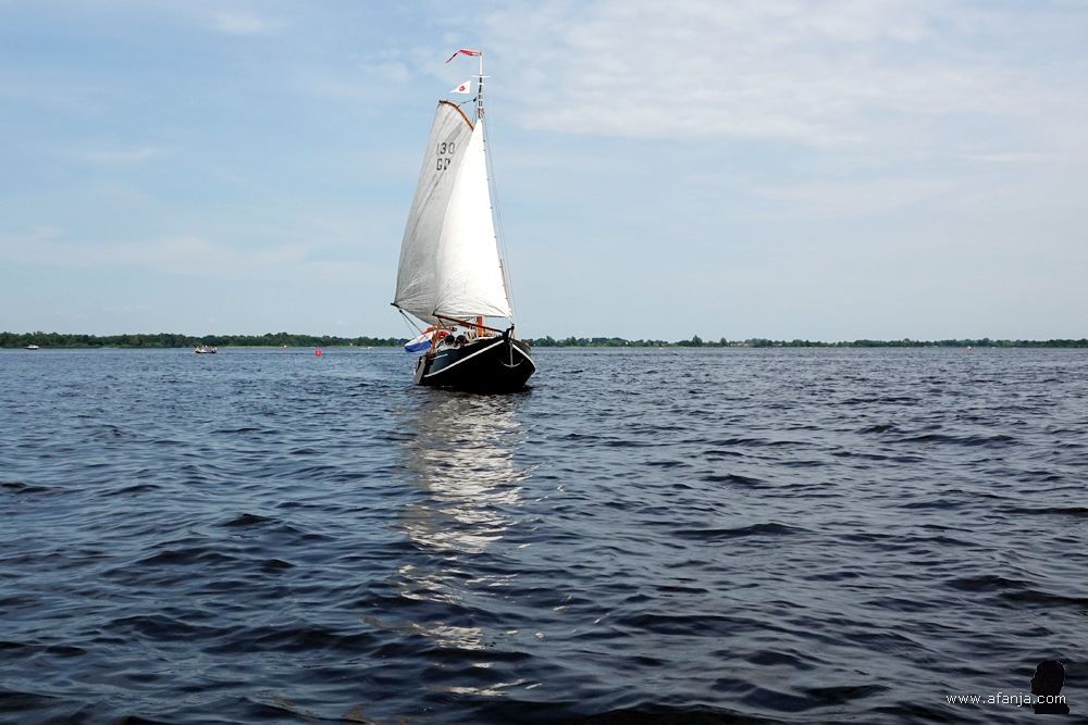 een mooie houten zeilboot draait achter ons langs