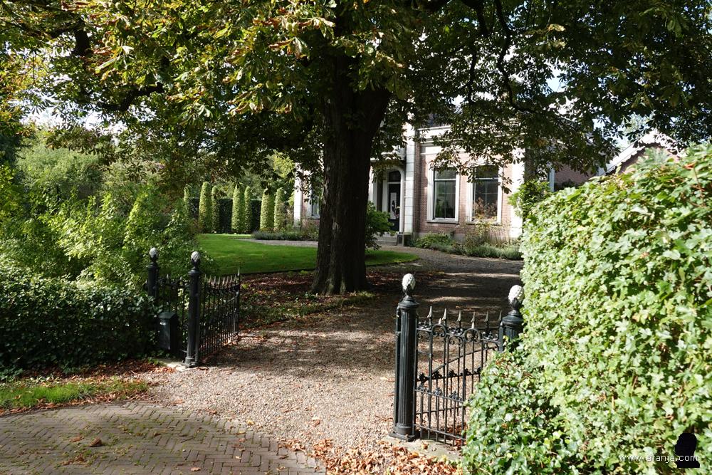 een huis met een grote voortuin en sierlijk hekwerk