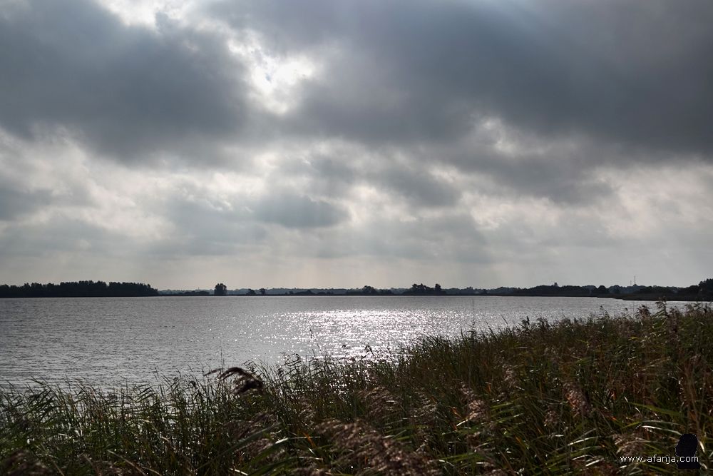 zonnestralen door de wolken laten het water oplichten
