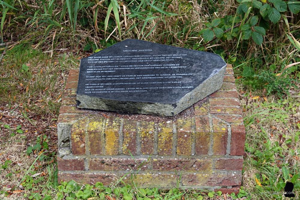 een platte steen met uitleg over 'Vrouwe Justitia'