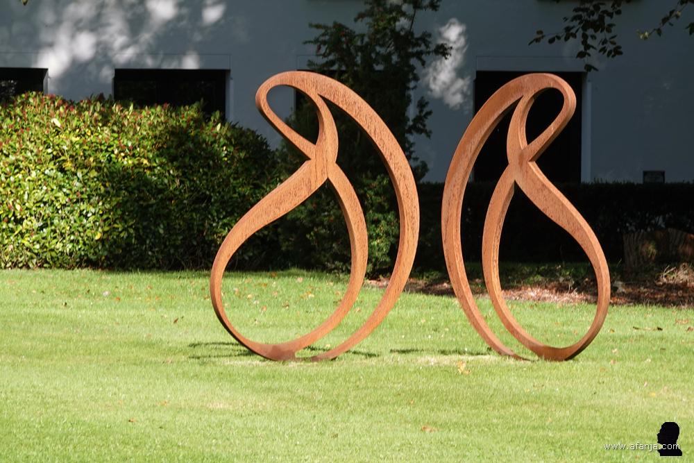 een kunstwerk van cortenstaal in de tuin