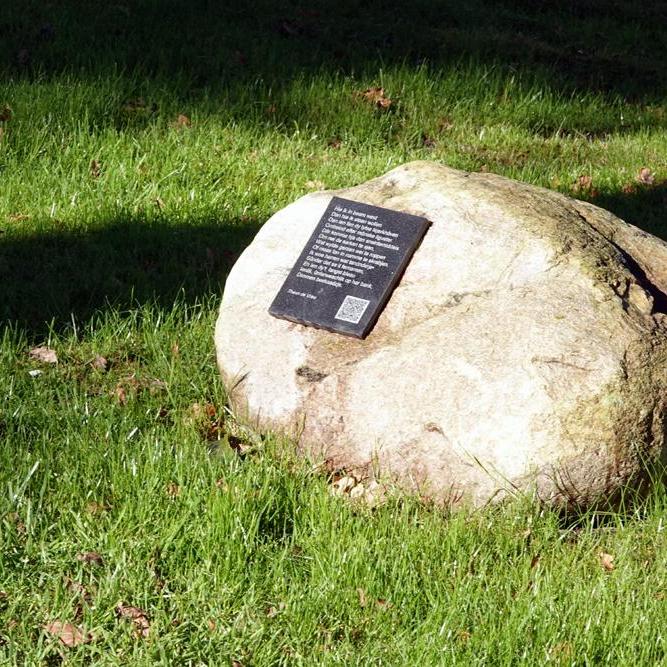 een zwerfsteen met een tegel waar een gedicht op staat