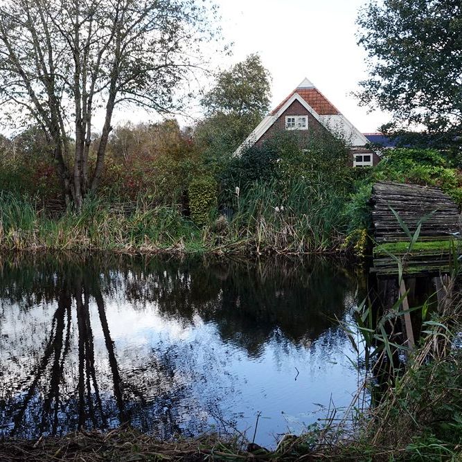 een woonboerderij met een gammel bruggetje over het Stroomkanaal bij Gersloot
