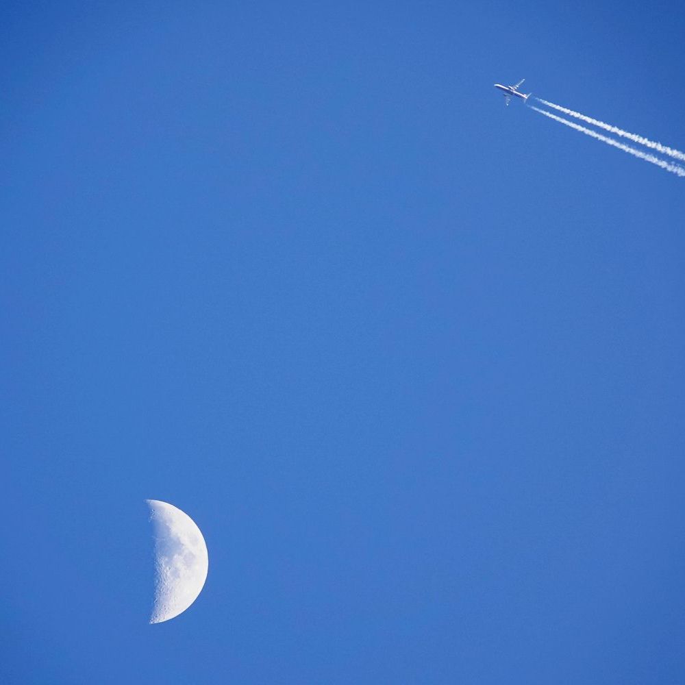 een straalvliegtuig vliegt voorbij de maan