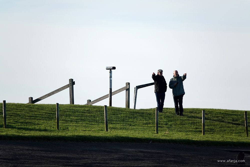 twee mensen staan op de dijk allebei ergens anders naar te wijzen