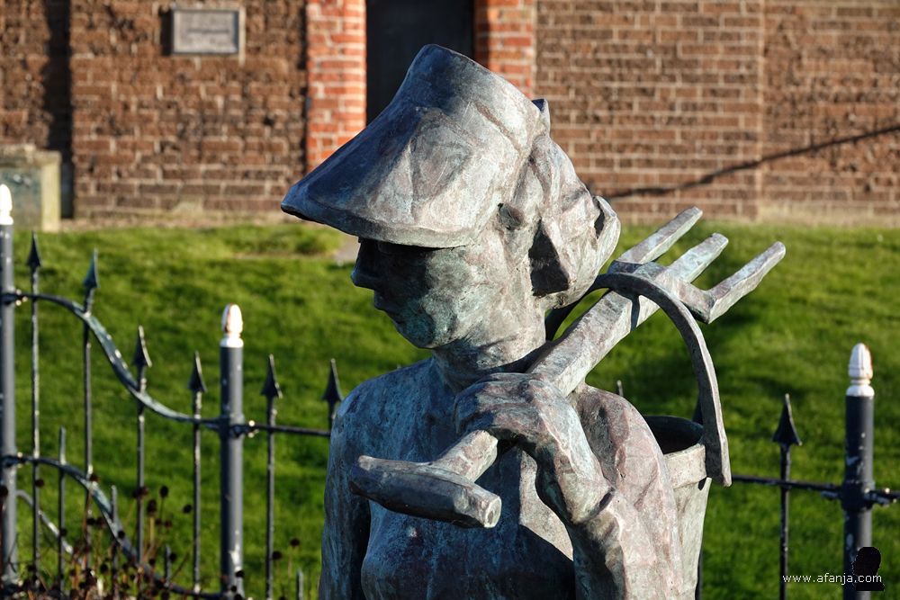 close-up van het beeld ‘de wjirmdolster’- de pierensteekster bij de Mariatsjerke in Wierum