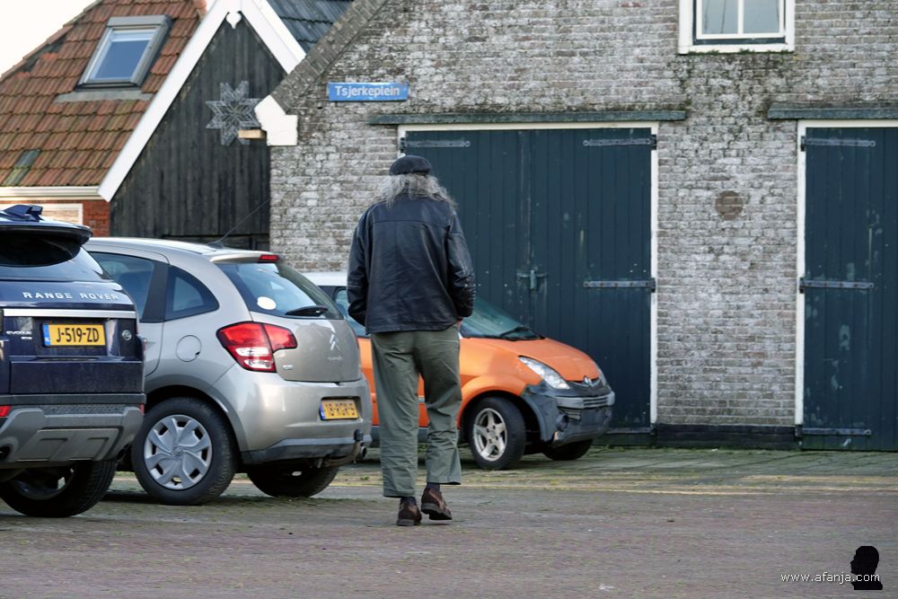 de langharige grijsaard wandelt het dorp in