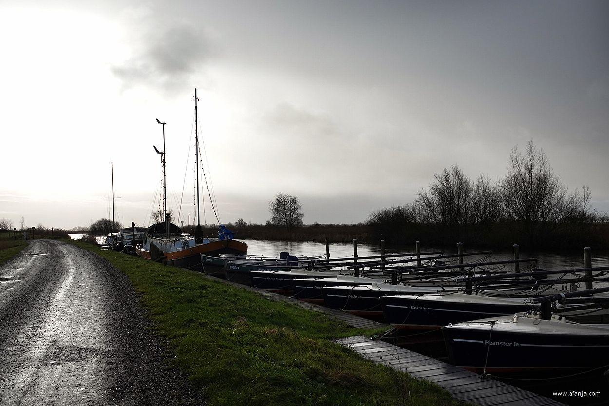 kleine zeilbootjes en een groter zeilschip langs de kant