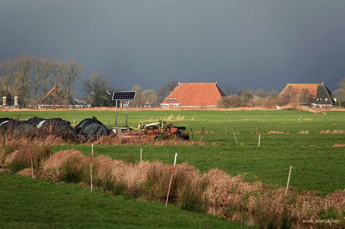 de zon licht de daken van boerderijen op tegen een buienlucht