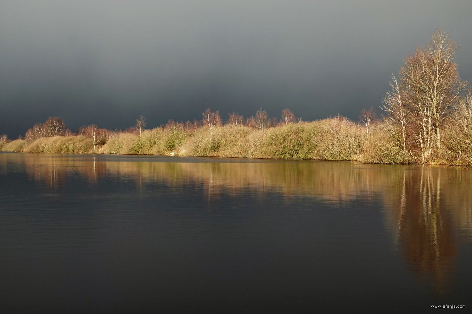 een bui met hagel of natte sneeuw nadert een pet gat in De Deelen, belicht door fel zonlicht