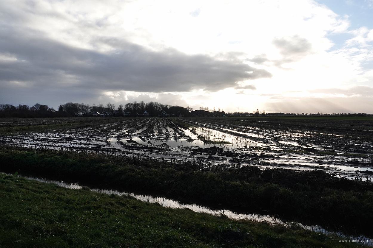 wolken en zon boven nat akkerland