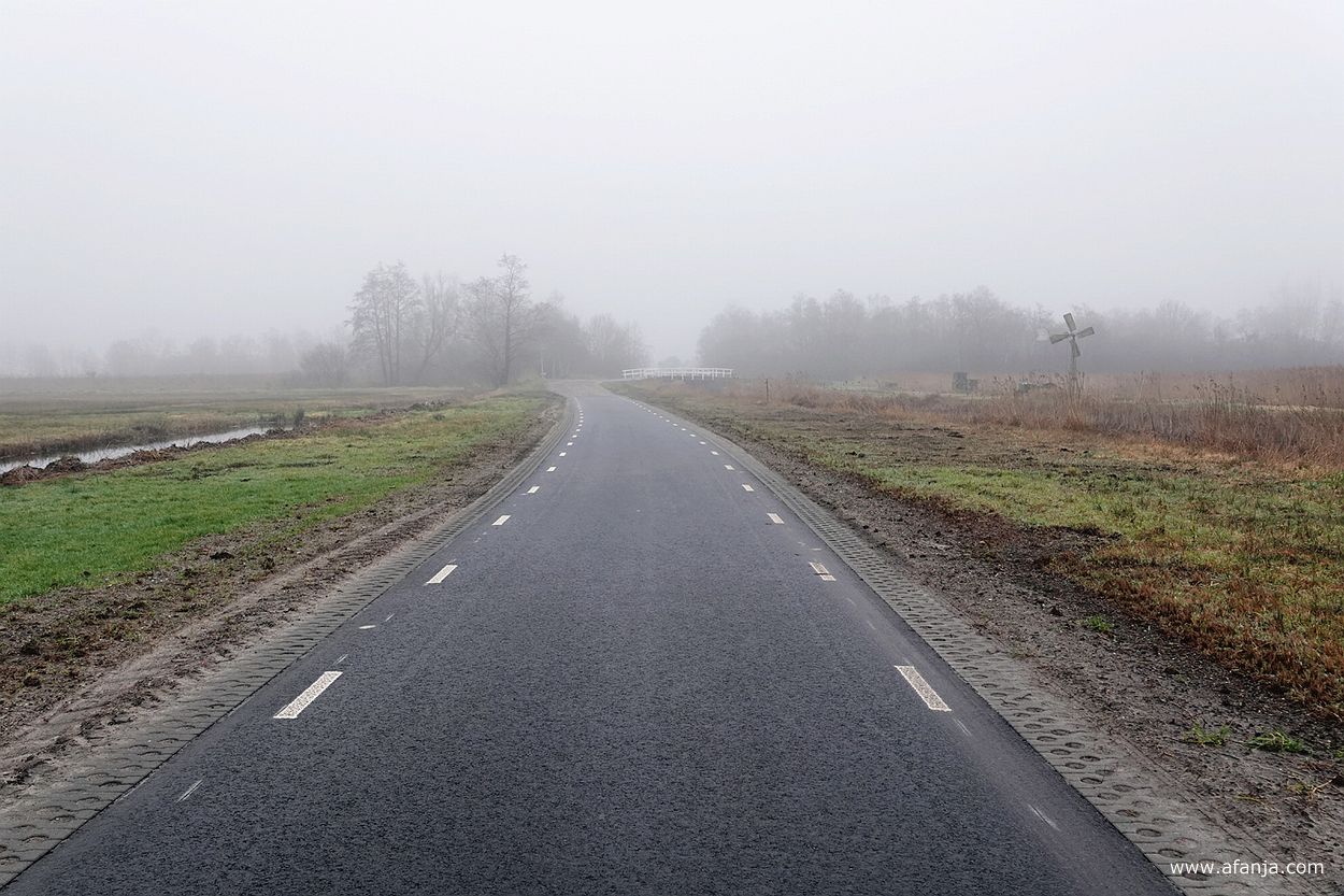 de Hoogeweg bij Kalenberg in de mist met rechts van de weg een kleine windmotor