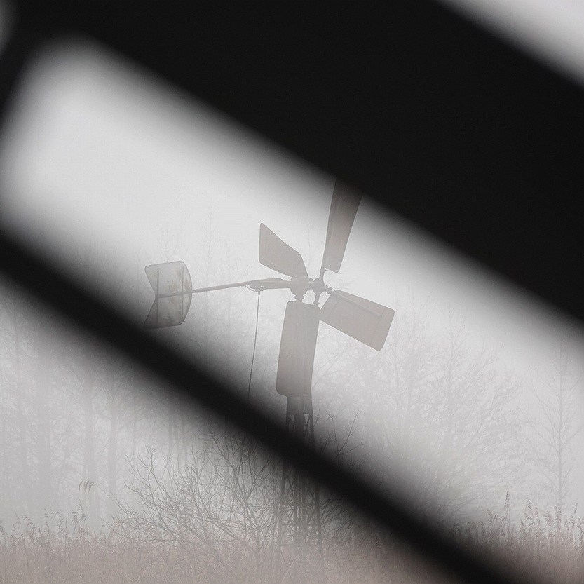 op de achtergrond een kleine windmotor in de mist