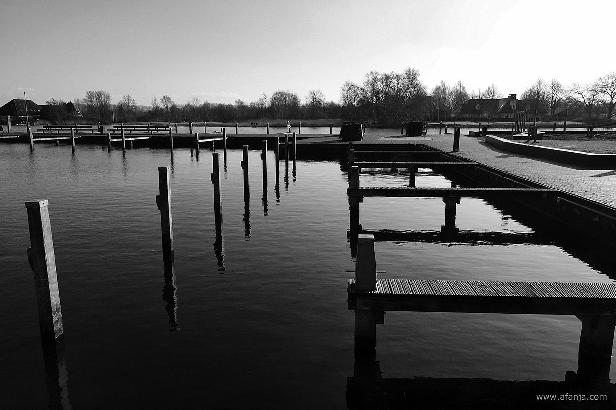 zwart/wit foto van meerpalen en aanlegsteigers in de jachthaven