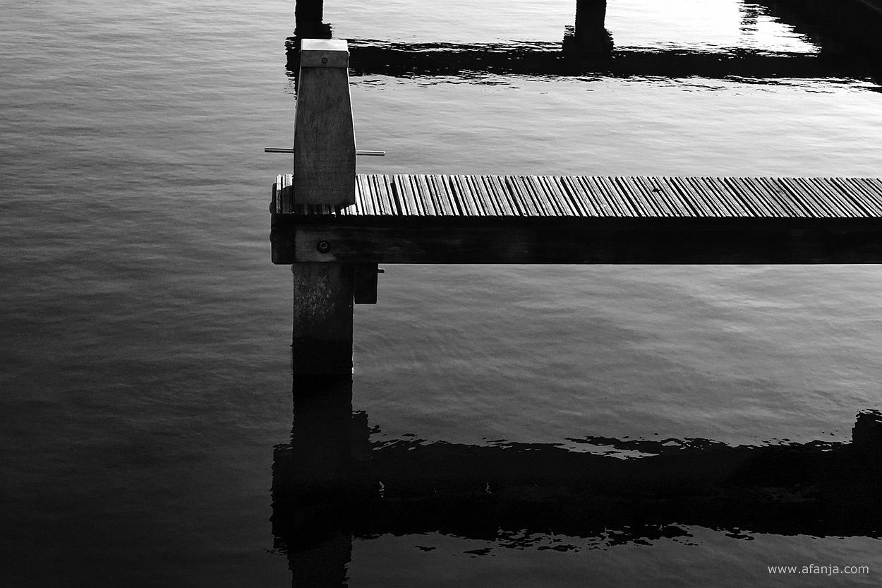 zwart/wit foto van meerpalen en aanlegsteigers in de jachthaven