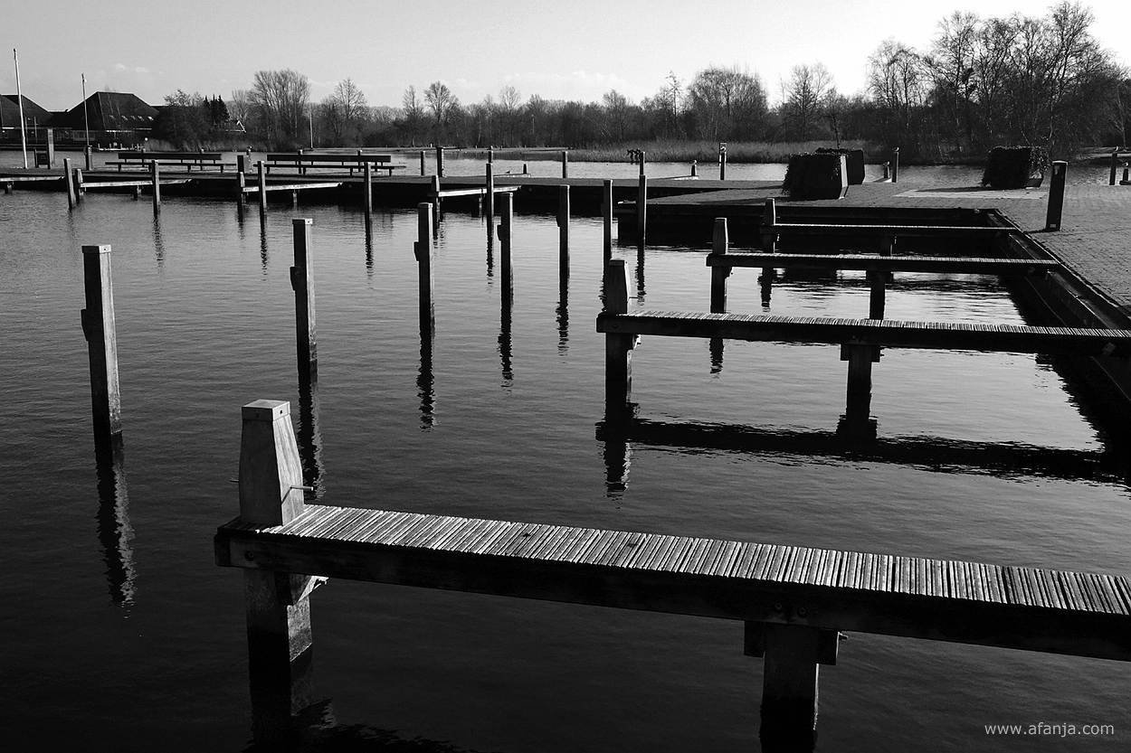 zwart/wit foto van meerpalen en aanlegsteigers in de jachthaven