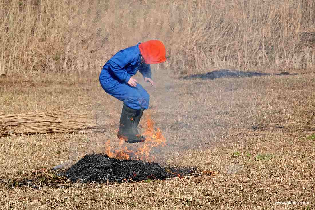 een jongen in een blauwe overall springt in het vuurtje