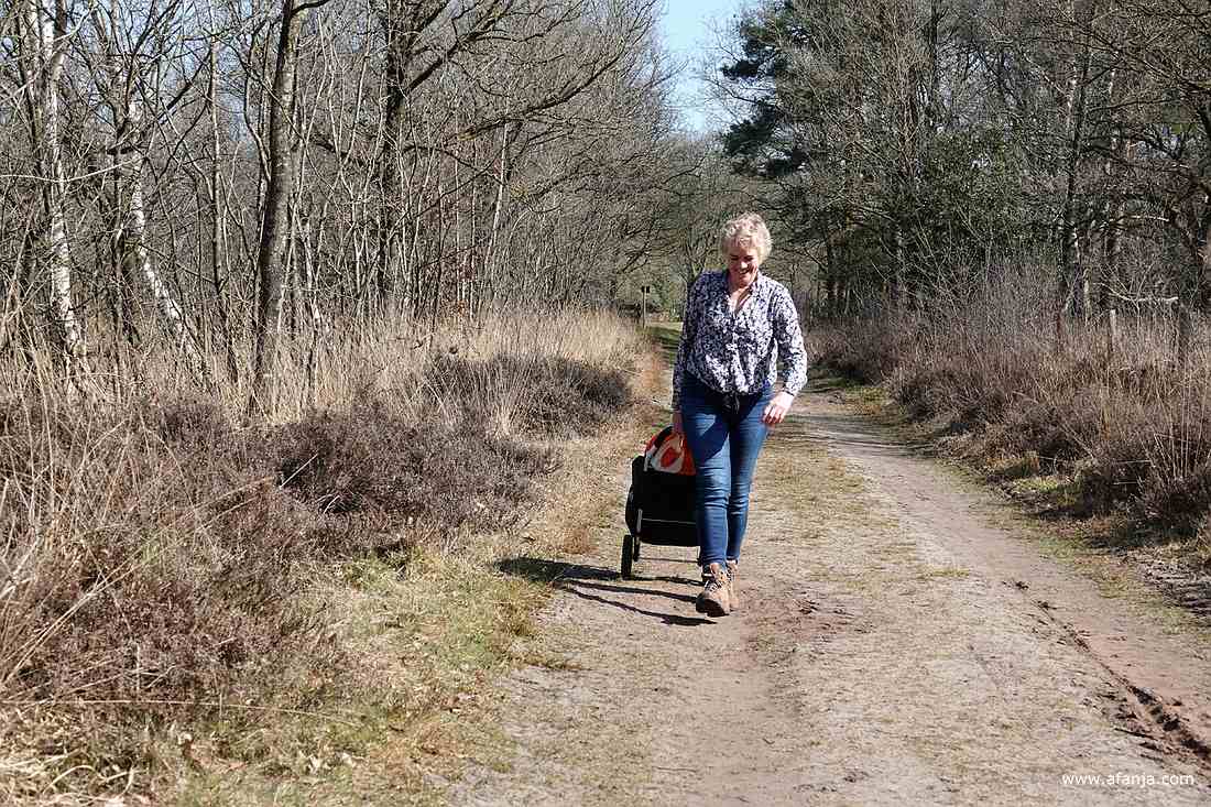 Jetske loopt over een zandpad met haar cameratas op wieltjes