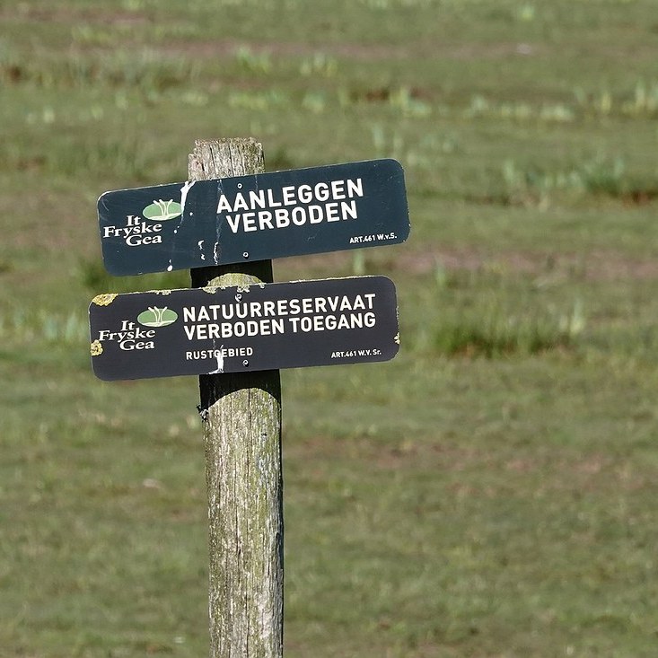 bordjes van It Fryske Gea met de tekst 'aanleggen verboden' en 'natuurreservaat - verboden toegang'