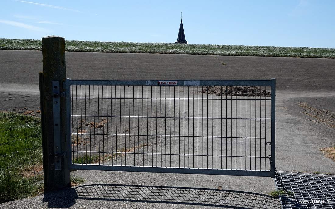 een halfgesloten hek aan het begin van de strekdam