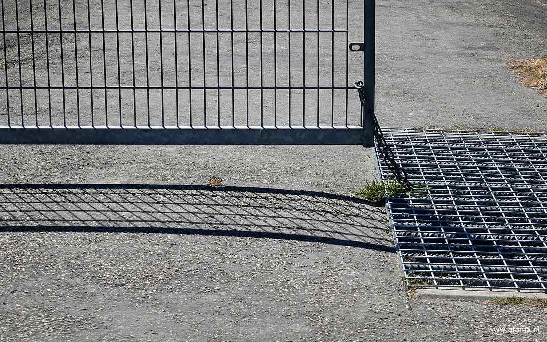 het onderste deel van een halfgesloten hek en een veerooster aan het begin van de strekdam