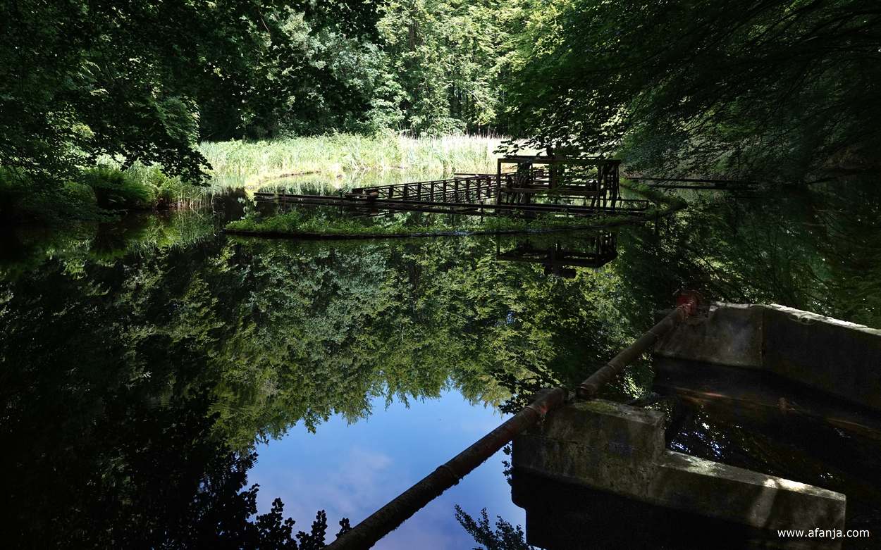 in de verte een roestige constructie die ooit gebruikt is voor onderzoeksdoeleinden, op de voorgrond een wateruitlaat