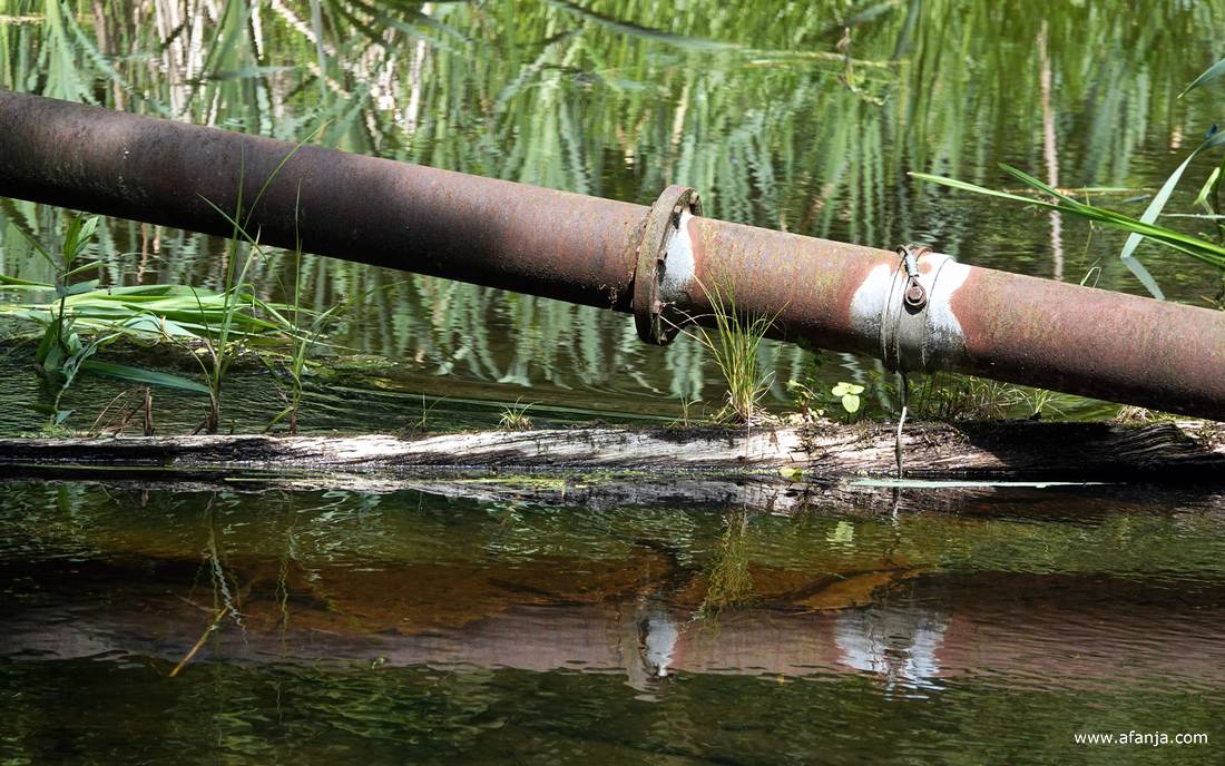 een roestige stang of buis hangt scheef in het water