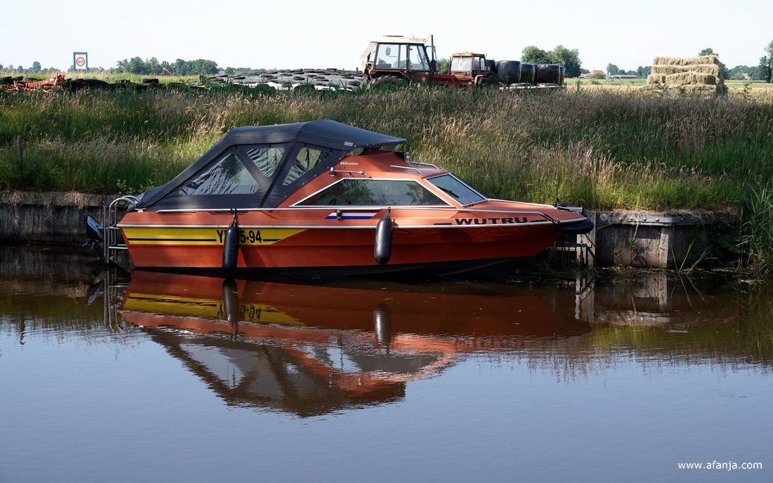 een snel bootje in het haventje van Smalle Ee, op de achtergrond zijn o.a. een paar oude trekkers en pakjes hooi te zien