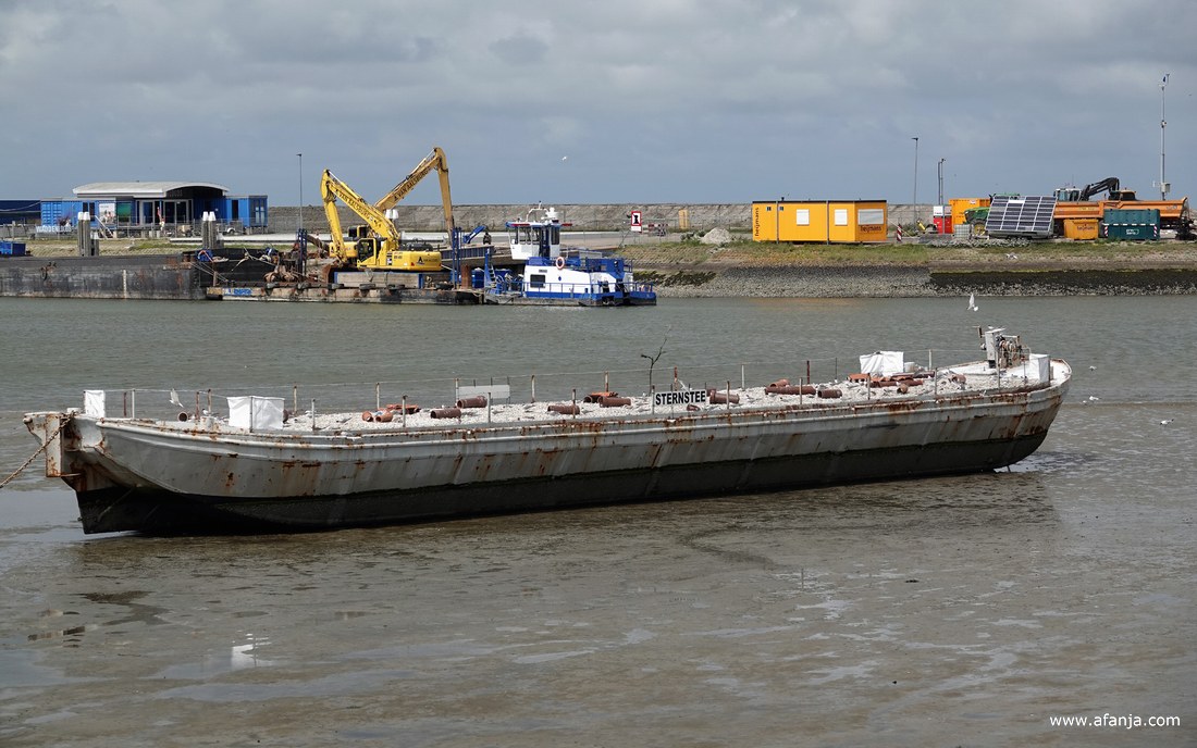 op het dek van de schuit met de naam 'Sternstee' ligt grind en schelpen en her en der liggen stenen afvoerbuizen