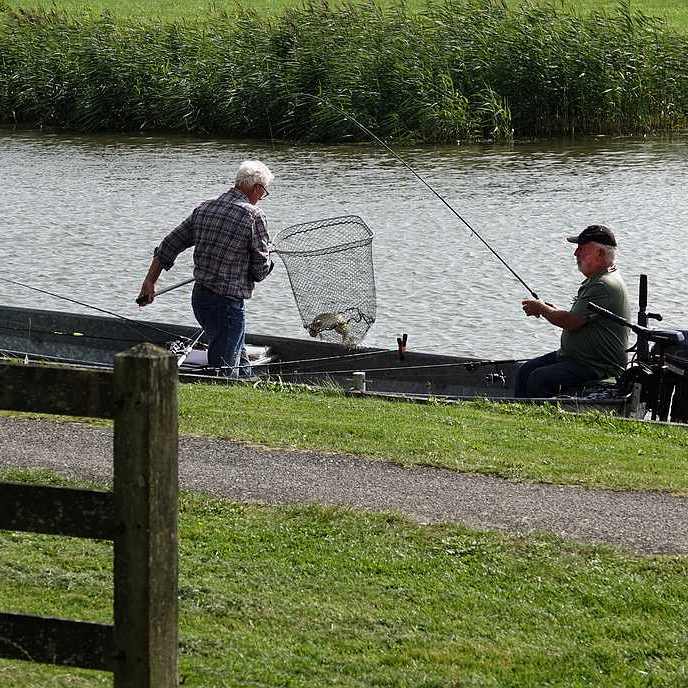 twee sportvissers lijken wat te hebben gevangen., met het schepnet wordt de vis omhoog gehaald