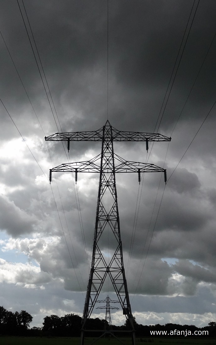 hoogspanningsmasten onder een donker wolkendek