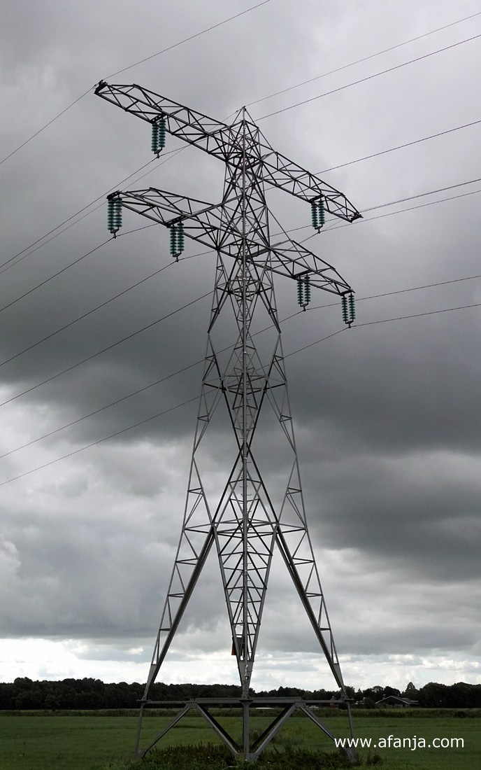 een hoogspanningsmast onder een donker wolkendek