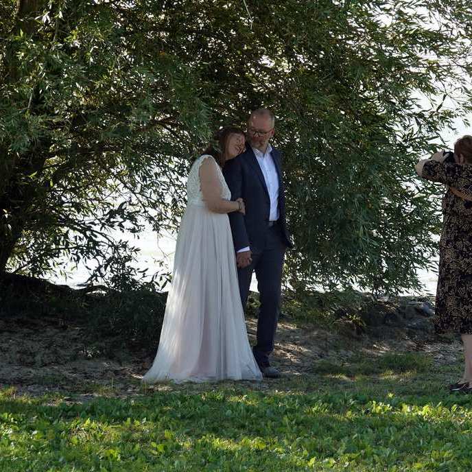 het bruidspaar wordt in de schaduw van de boom gefotografeerd