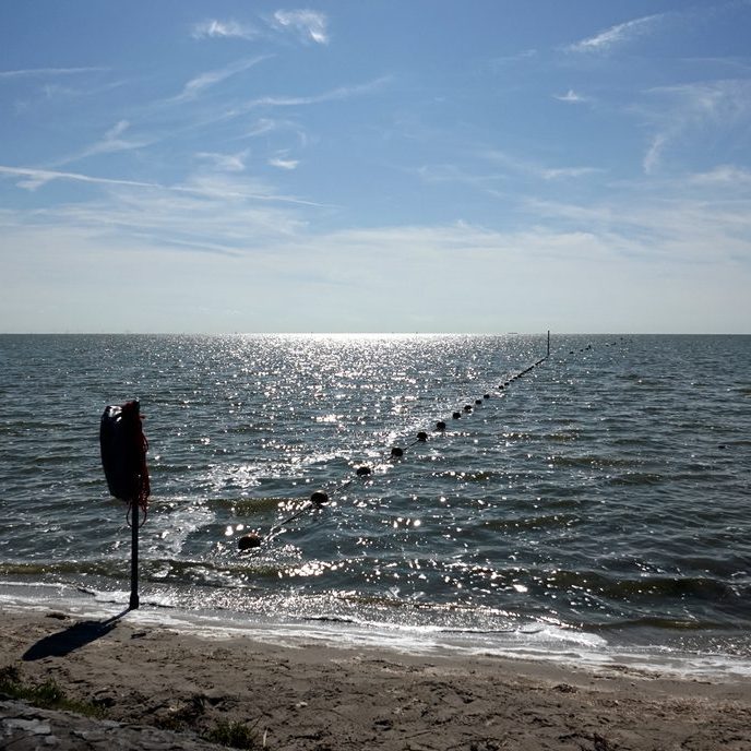 de veiligheidslijn met balletjes, links is voor de surfers, recht is voor de zwemmers