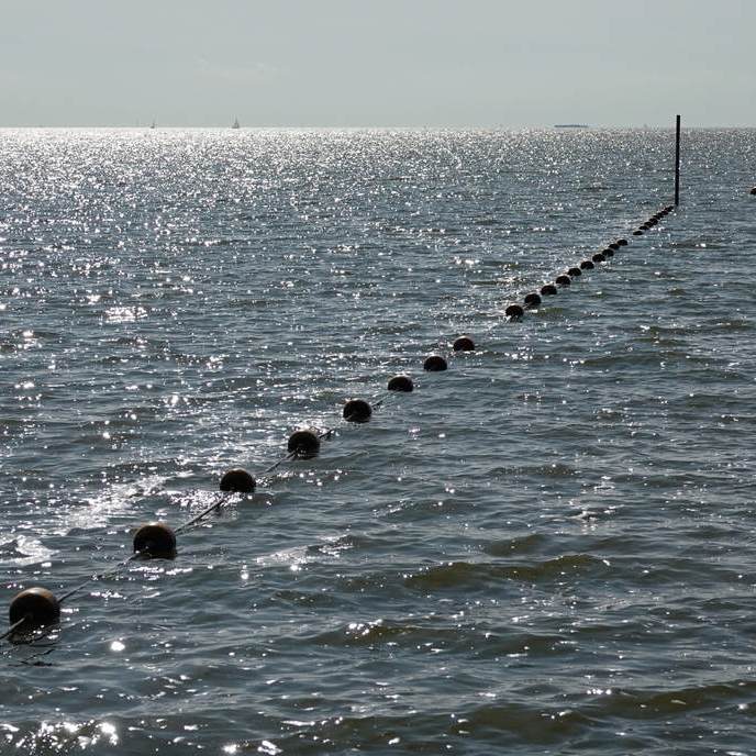 de veiligheidslijn met balletjes, links is voor de surfers, recht is voor de zwemmers