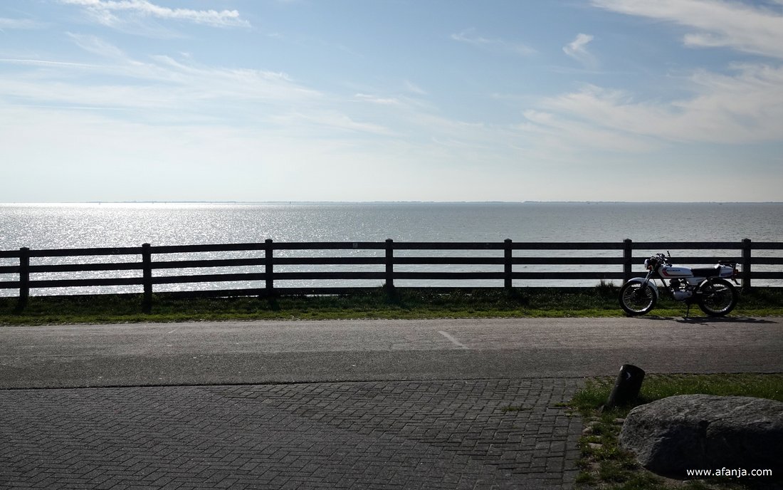 tegen hek langs het Reaklif staat een brommer geparkeerd