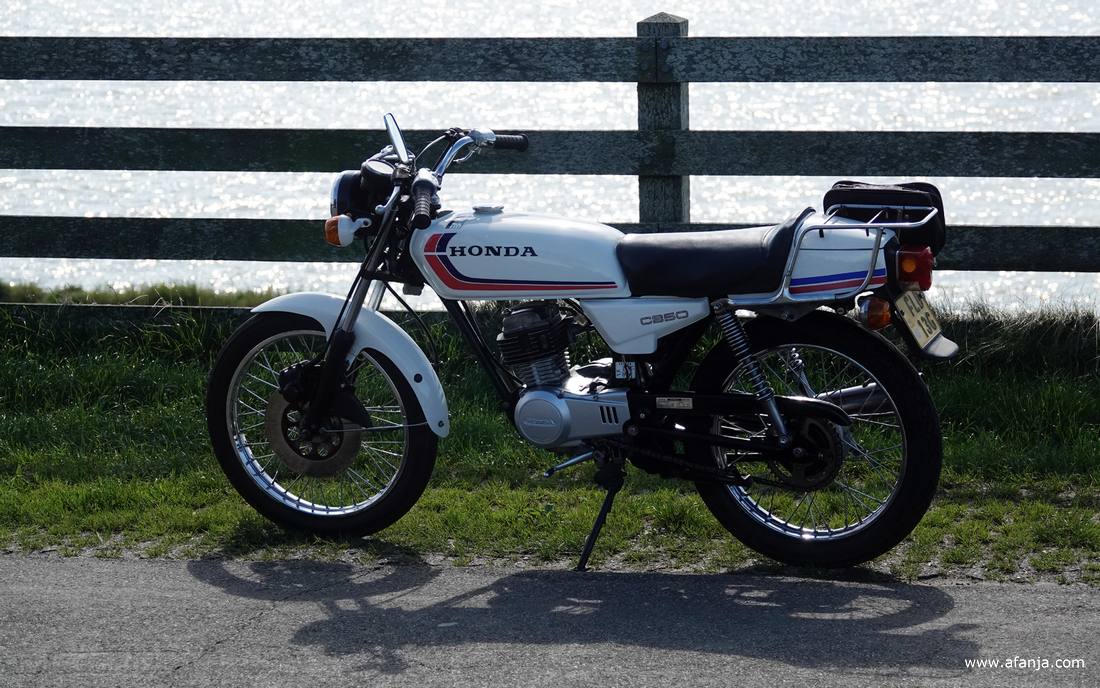 een wart-witte Honda brommer staat bij hek hek op Reaklif