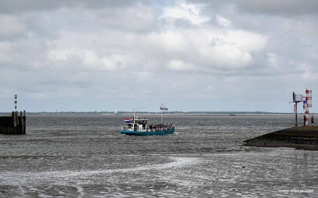 de 'Vriendschap' vaart uit naar Schiermonnikoog, op de achtergrond te zien met zijn twee vuurtorens