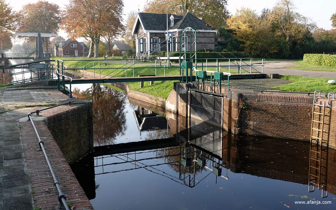 een sluis in de Opsterlandse Compagnonsvaart met op de achtergrond de sluiswachterswoning