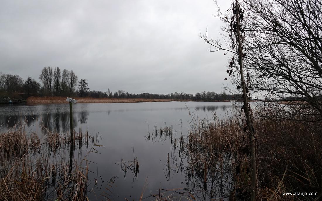 in een meertje staat een paal met een bordje