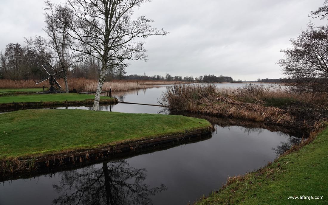 een landschap met verderop een meertje en een tjasker