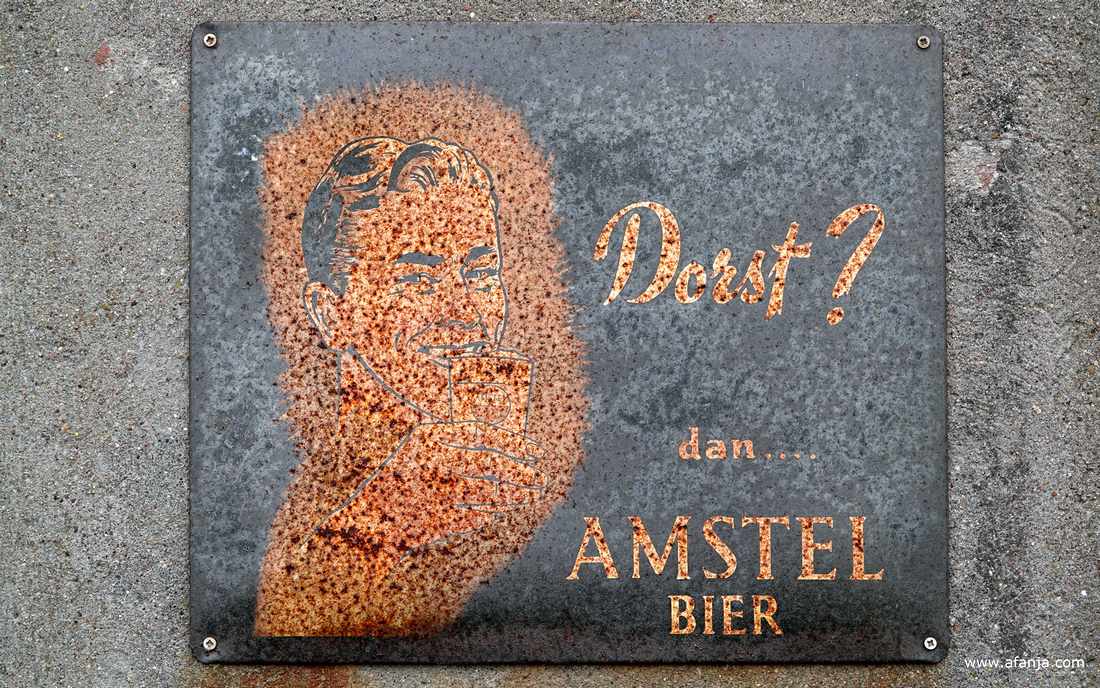 oud en roestig reclamebord voor Amstel bier op de zijgevel