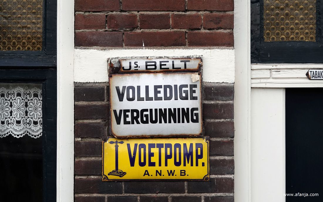 bordjes op de gevel van café de Moespot