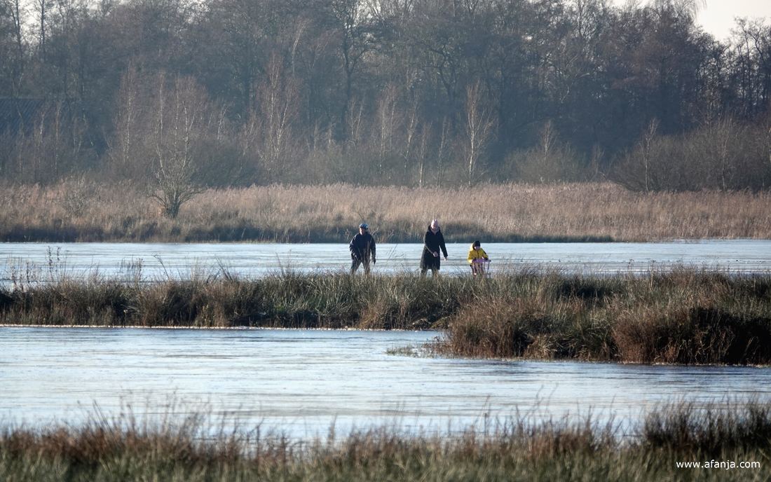 twee volwassenen en een kind achter een stoel op dun ijs