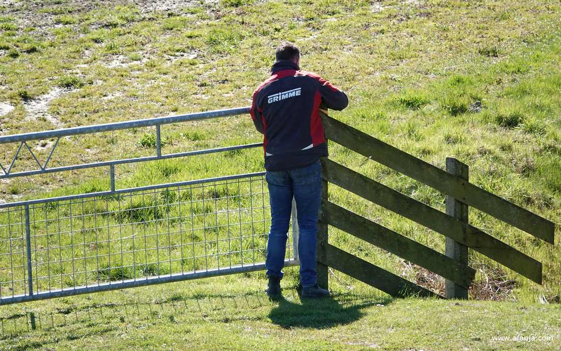 een boer heeft aan de Seewei zijn trekker verlaten om een hek te openen