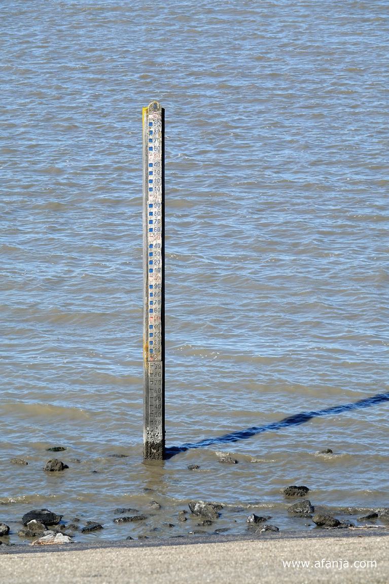 een oude peilschaal aan de voet van de dijk in de Waddenzee
