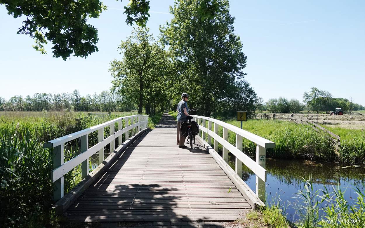Aafje staat met de fiets aan de hand op een bruggetje