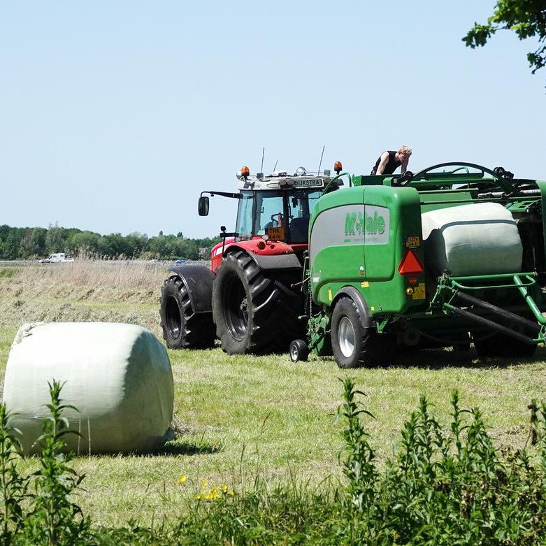 de boer is op de grote balenpers geklommen om een probleem te verhelpen